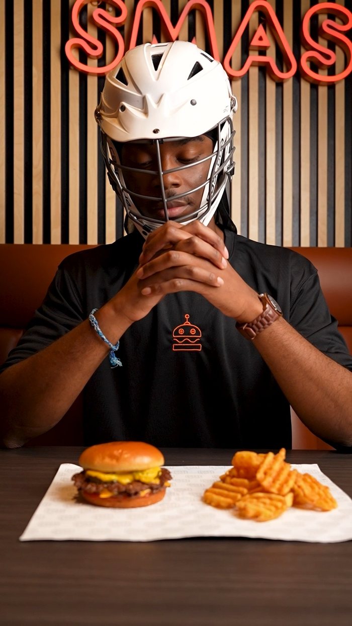 Keran in a lacrosse helmet at Phat Buns with a burger and fries